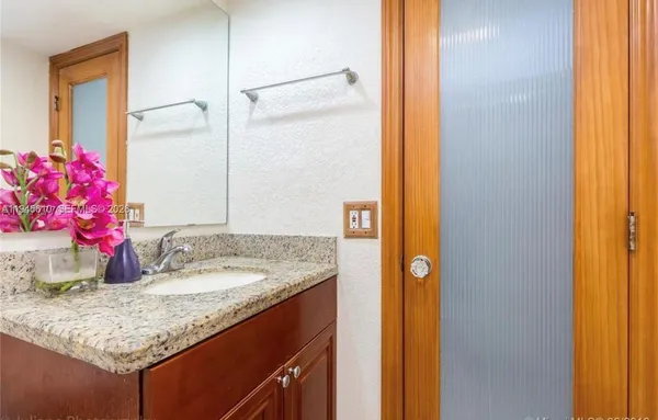 a bathroom with a granite countertop sink and a mirror