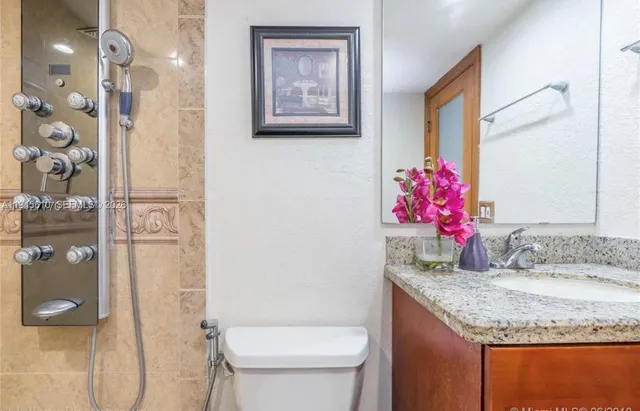 a bathroom with a granite countertop sink a toilet and shower