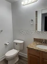 a bathroom with a granite countertop toilet sink and mirror