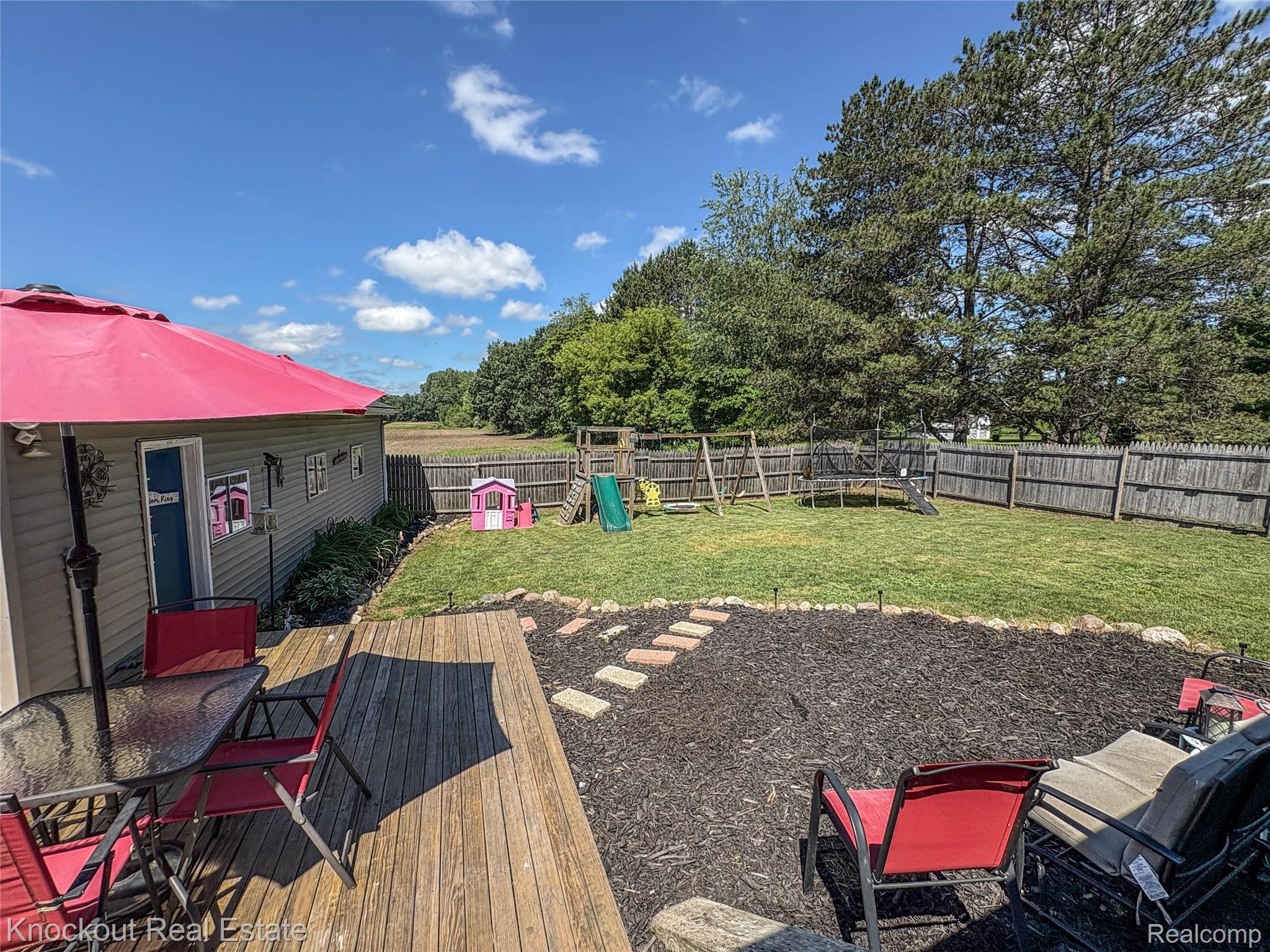 7760 Bell Road Birch Run, MI 48415 - Photo 53 of 68 Expansive backyard featuring a wood deck, manicured lawn, and natural wood privacy fencing