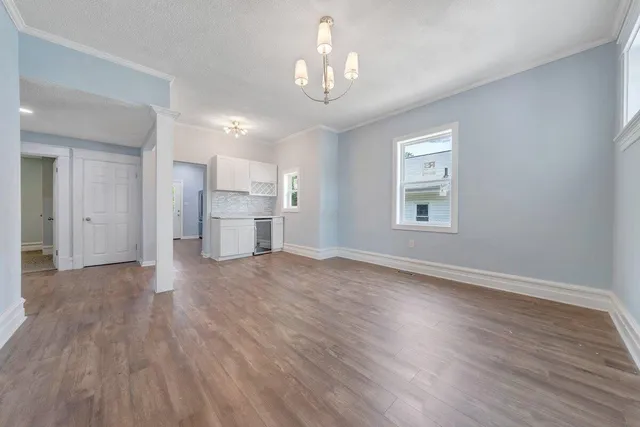 an empty room with wooden floor chandelier and windows