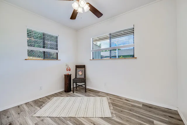 a view of empty room with wooden floor and fan