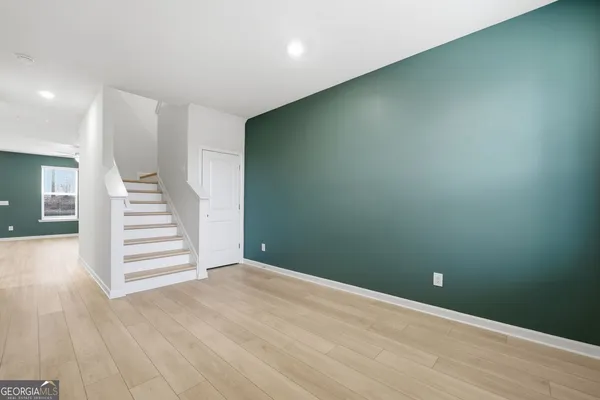 an empty room with wooden floor and stairs