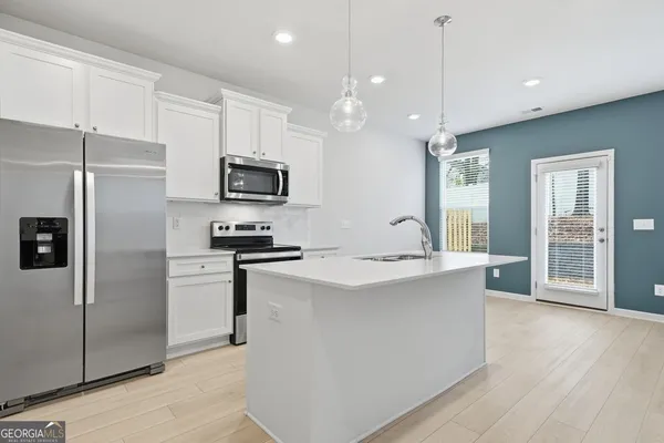 a kitchen with stainless steel appliances granite countertop a refrigerator a stove a sink and a microwave