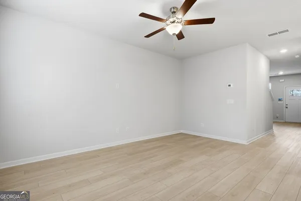 an empty room with wooden floor and fan