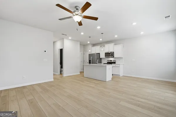 a view of kitchen with kitchen island stainless steel appliances refrigerator stove top oven and cabinets