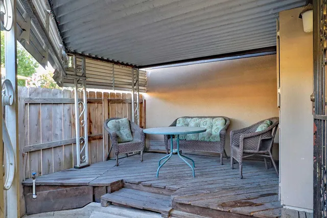 a view of a patio with table and chairs with wooden floor and fence