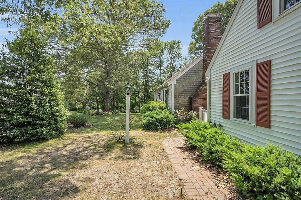 89 Kingswear Circle Dennis, MA 02660 - Photo 11 of 40 a pathway of a house with potted plants and large tree