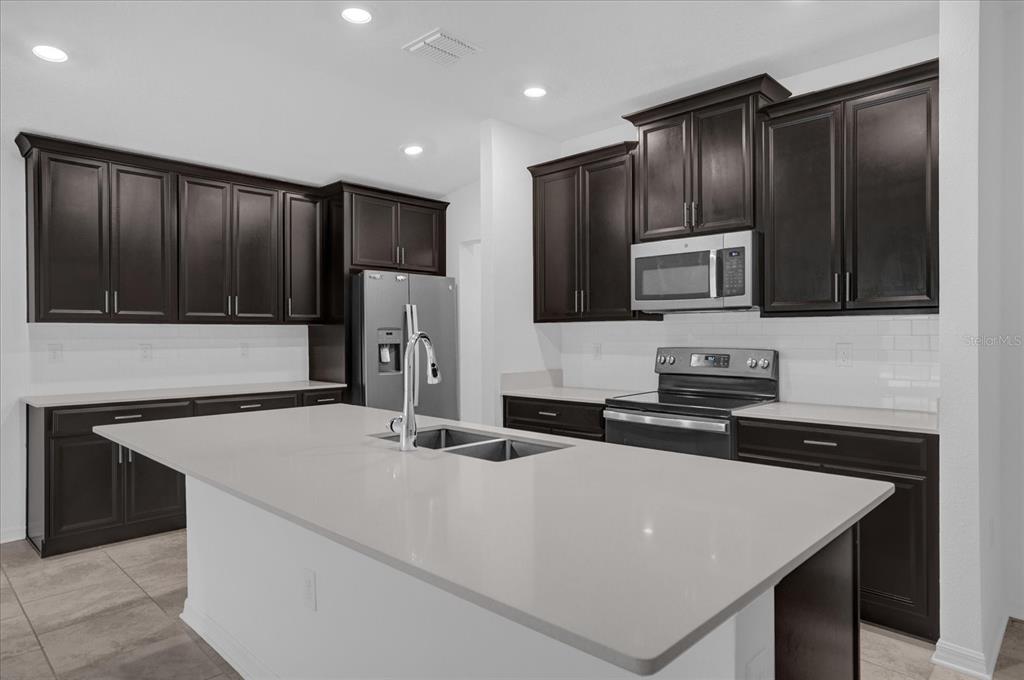 4712 Magnetite Loop Mount Mount Dora, FL 32757 - Photo 4 of 15 a kitchen with stainless steel appliances a microwave sink refrigerator and cabinets