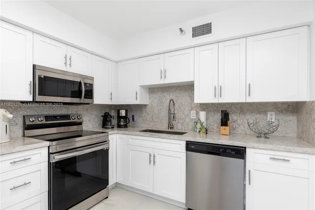 a kitchen with white cabinets stainless steel appliances and sink