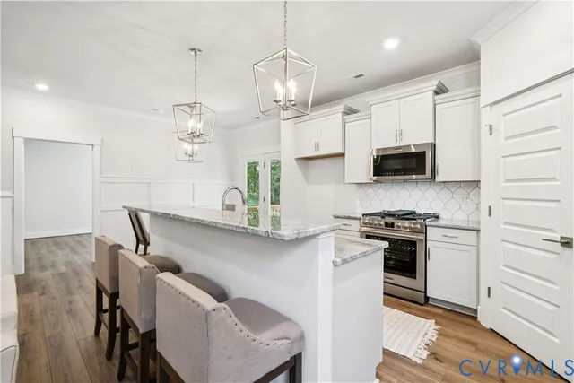 a kitchen with stainless steel appliances granite countertop a sink a stove a refrigerator a dining table and chairs