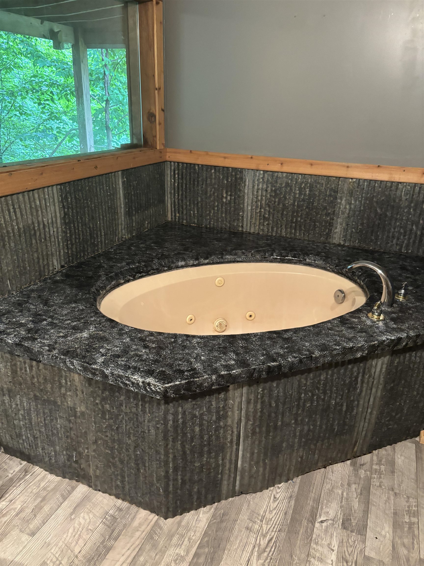 7462 Campground Road Drummonds, TN 38023 - Photo 25 of 31 Corner jetted tub with dark stone-look surround and wood-finish flooring