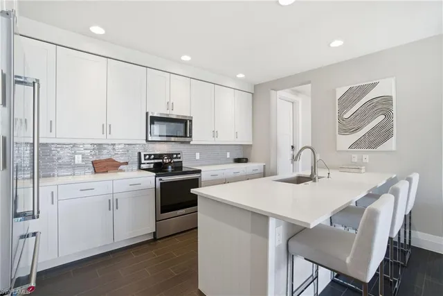 a kitchen with a sink white cabinets and stainless steel appliances