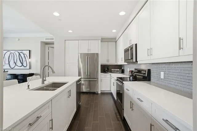 a kitchen with a sink dishwasher a refrigerator a stove and white cabinets with wooden floor