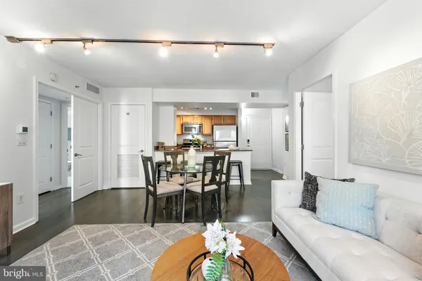 a living room with furniture a dining table and a refrigerator