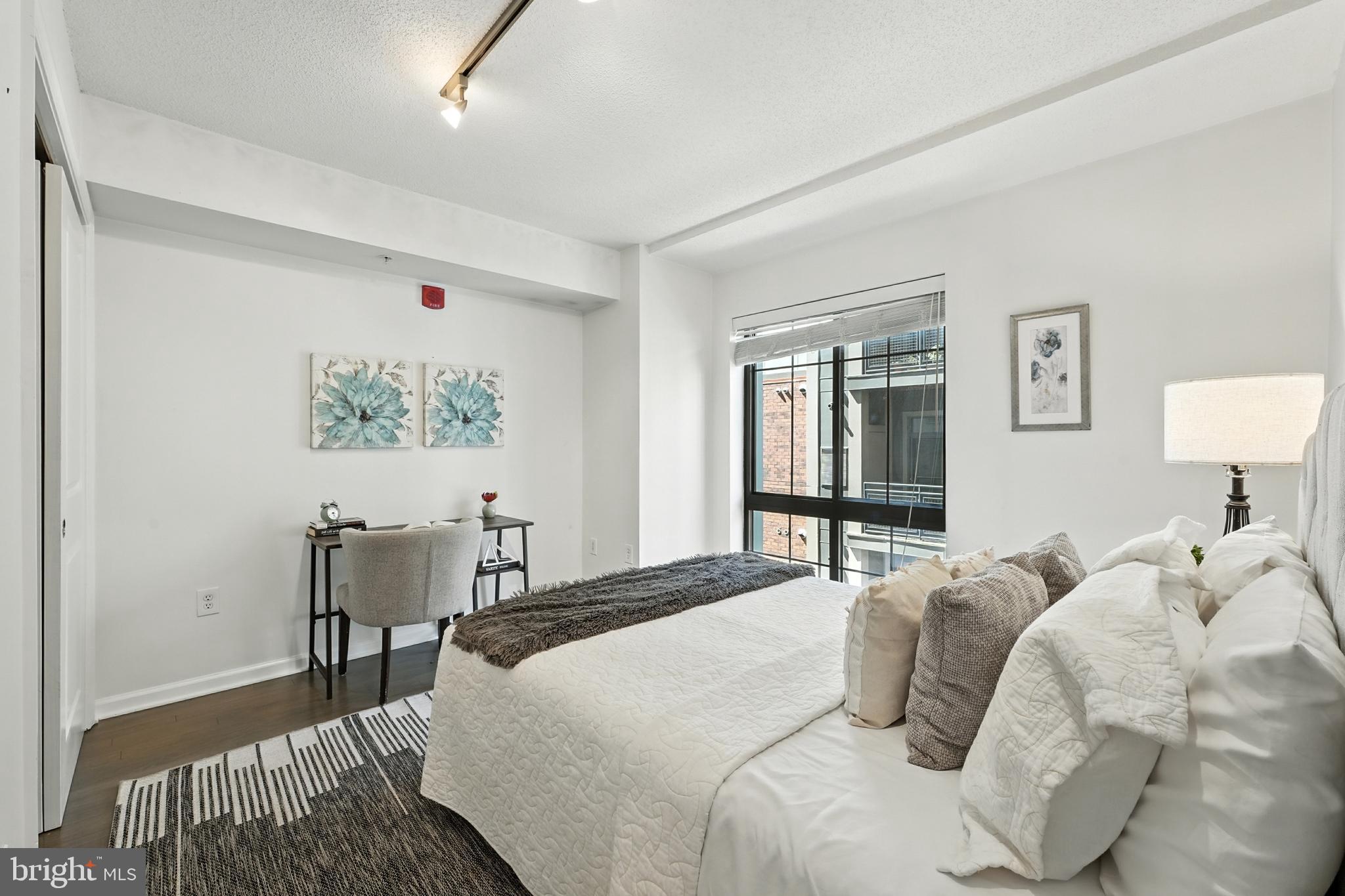 7923 Eastern Avenue Northwest, Unit 303 Silver Spring, MD 20910 - Photo 14 of 38 a bedroom with a bed and a lamp on table