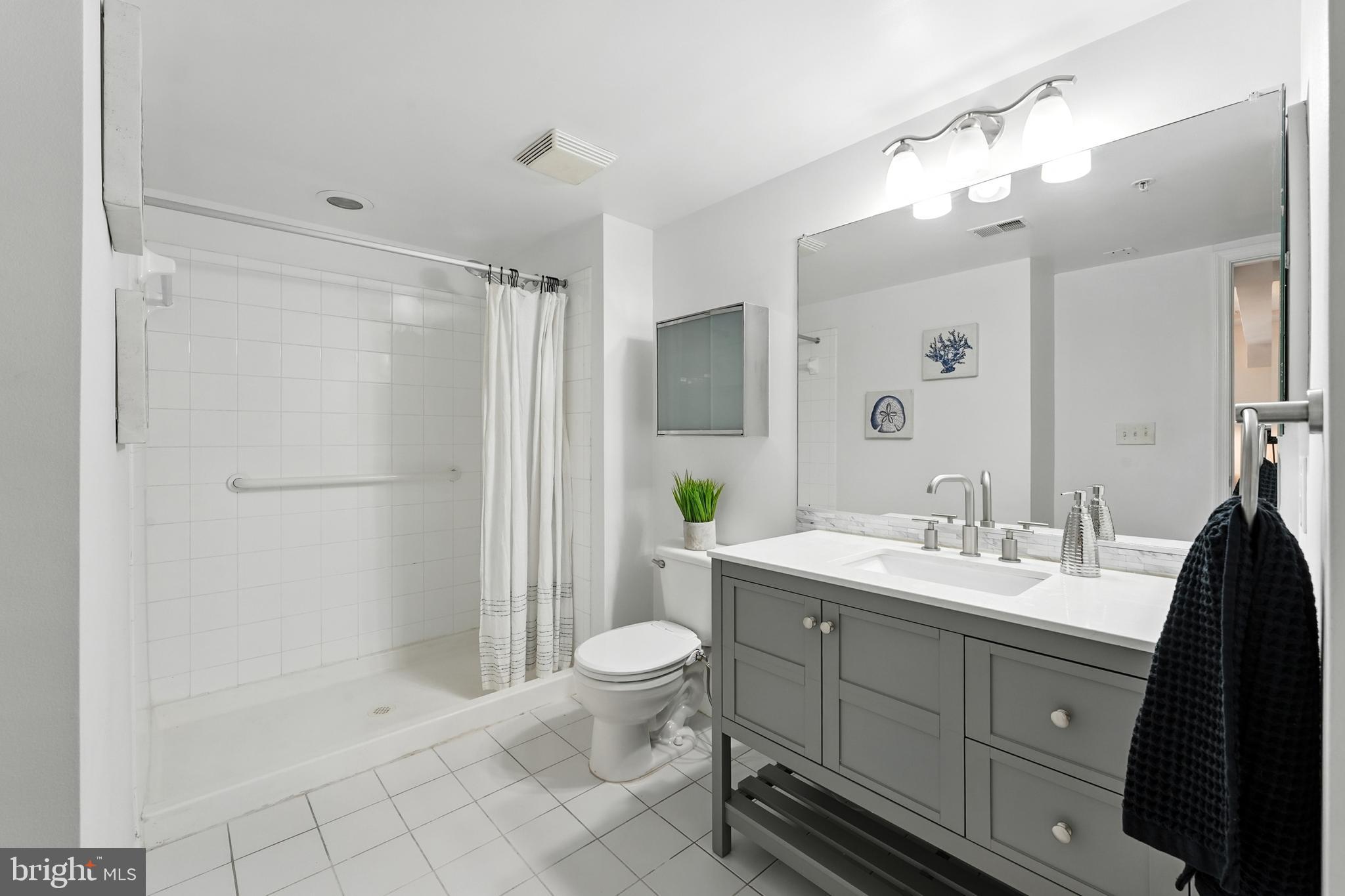 7923 Eastern Avenue Northwest, Unit 303 Silver Spring, MD 20910 - Photo 26 of 38 a spacious bathroom with a double vanity sink toilet mirror and shower