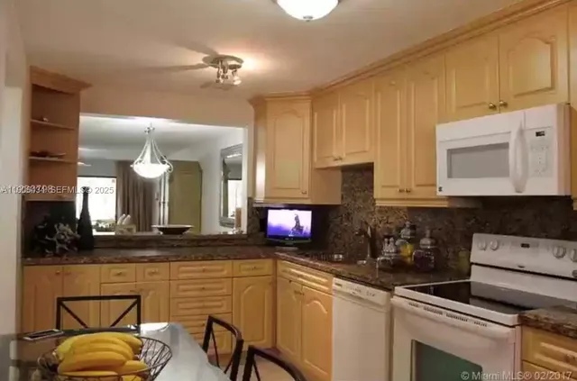 a kitchen with kitchen island granite countertop a sink cabinets and stainless steel appliances