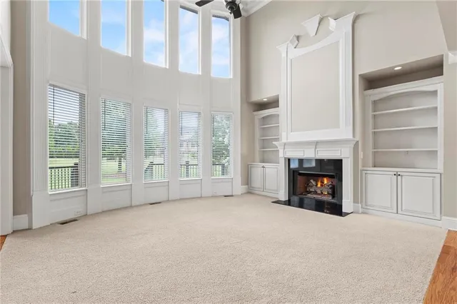 a view of an empty room with wooden floor fireplace and a window