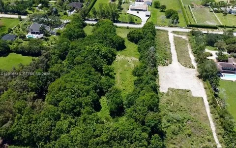 an aerial view of residential house with outdoor space and trees all around