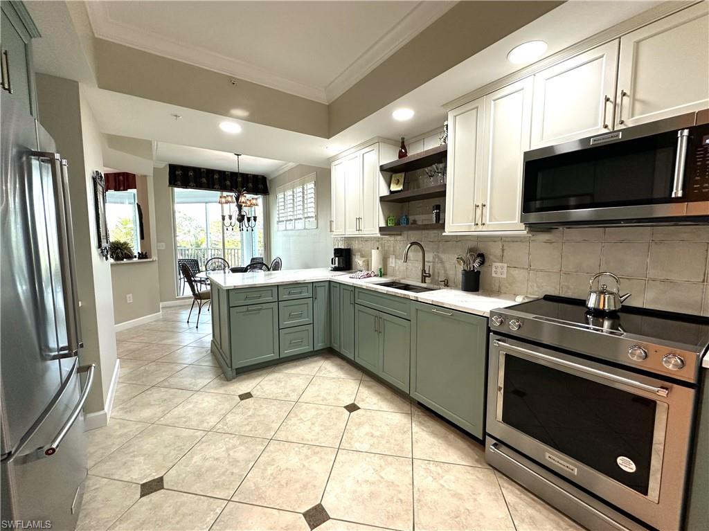 325 Dunes Boulevard, Unit 306 Naples, FL 34110 - Photo 11 of 40 a kitchen with stainless steel appliances a stove a sink a microwave and cabinets