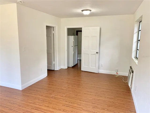 a view of an empty room with wooden floor and a window