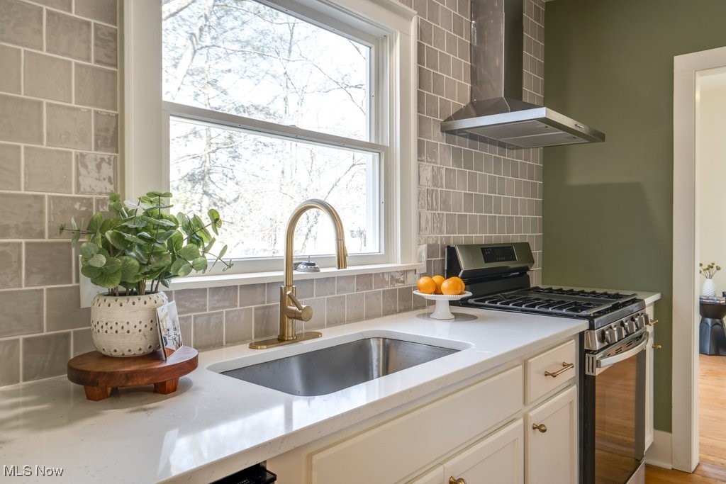 199 Edgerton Road Akron, OH 44303 - Photo 22 of 49 Kitchen featuring tasteful backsplash, wall chimney range hood, light countertops, gas stove, and a sink