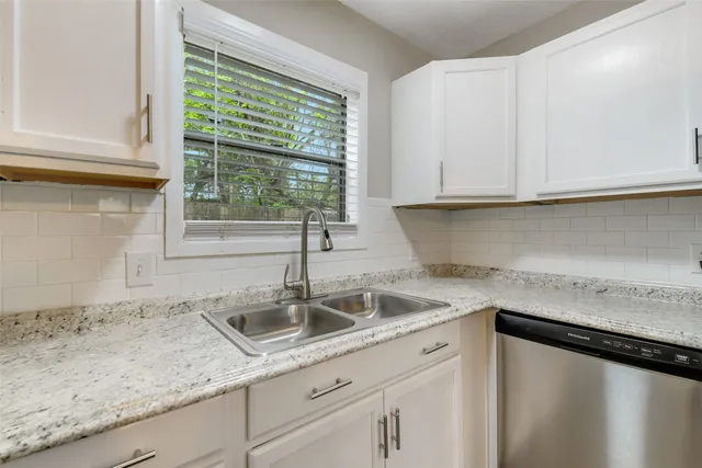 a kitchen with granite countertop a sink and white cabinets