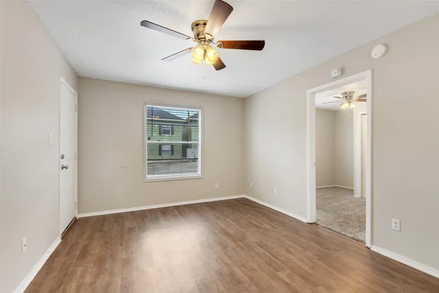 an empty room with wooden floor and windows
