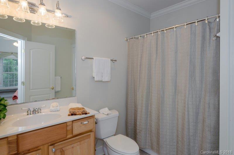105 Spring Path, Unit 77 Hendersonville, NC 28739 - Photo 19 of 21 a bathroom with a sink a toilet a mirror and shower curtain