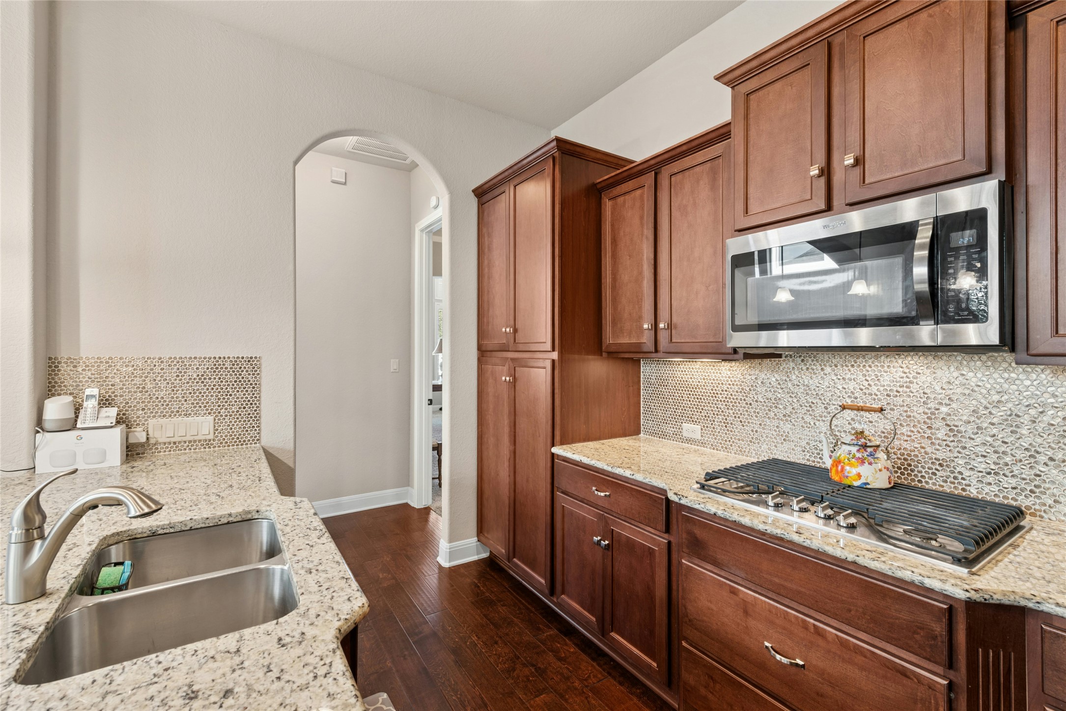 116 Evolutions Path Lakeway, TX 78738 - Photo 10 of 34 Kitchen with arched walkways, stainless steel appliances, dark wood-style floors, light stone countertops, and decorative backsplash
