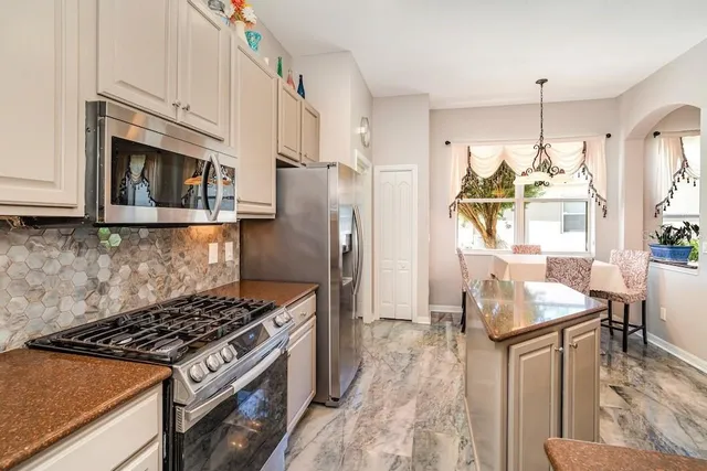 a kitchen with granite countertop a stove a sink dishwasher a refrigerator a microwave oven with cabinets and wooden floor