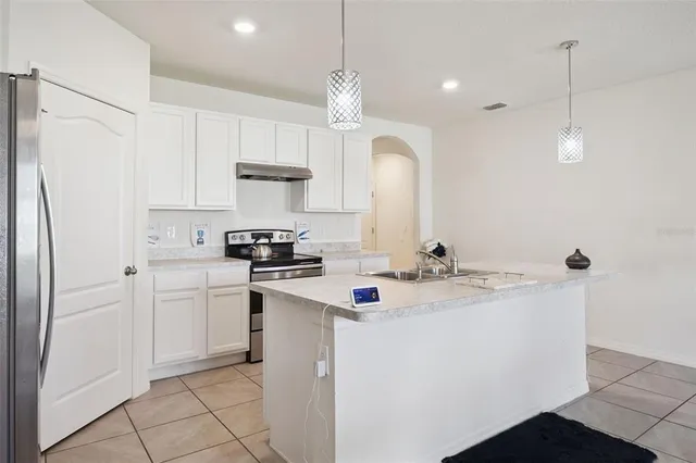 a kitchen with a sink a stove a refrigerator and white cabinets