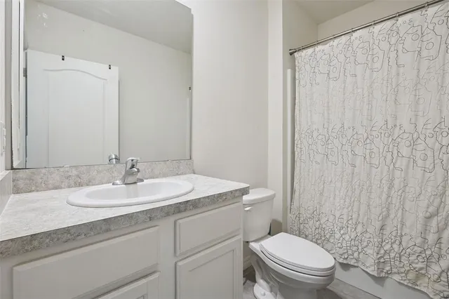 a bathroom with a granite countertop sink toilet and mirror