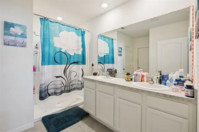 a bathroom with double vanity sinks a mirror and a bathtub