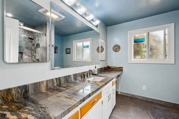 a bathroom with a granite countertop sink a toilet and a mirror
