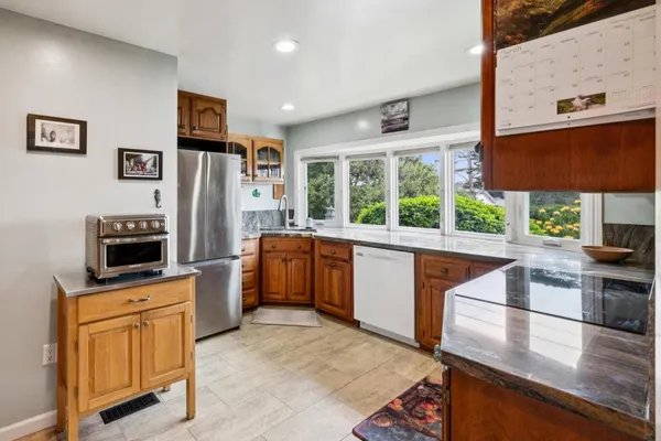a kitchen with stainless steel appliances wooden cabinets a sink and a large window