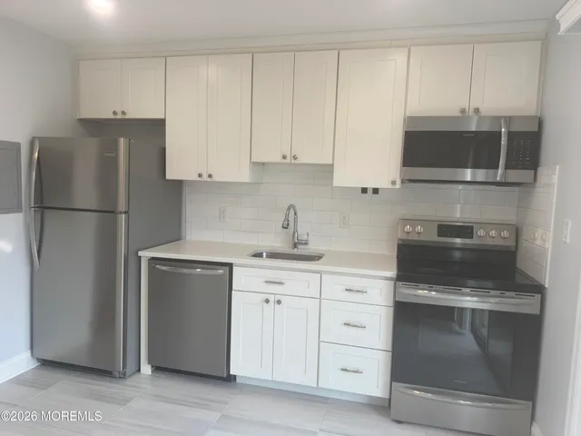 a kitchen with white cabinets and white appliances
