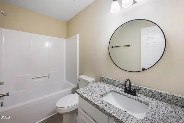 a bathroom with a granite countertop toilet a sink and a mirror