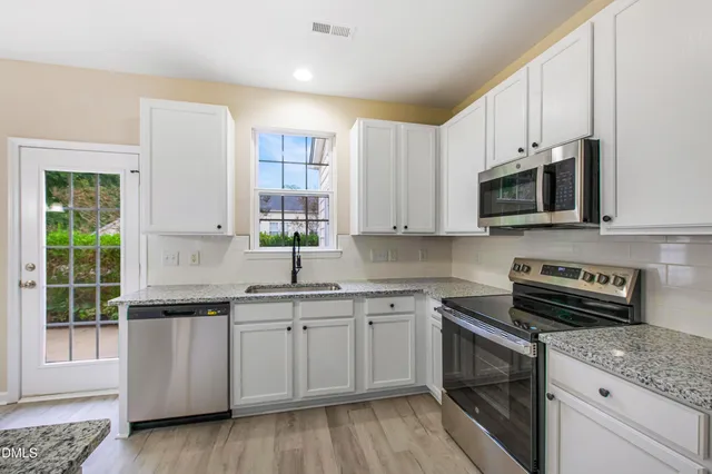 a kitchen with stainless steel appliances granite countertop a stove a sink and a microwave