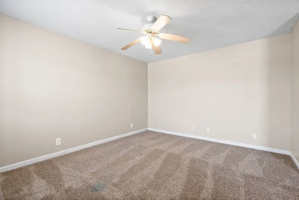 an empty room with a chandelier fan and windows
