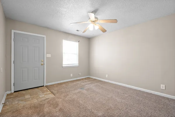 an empty room with windows and fan