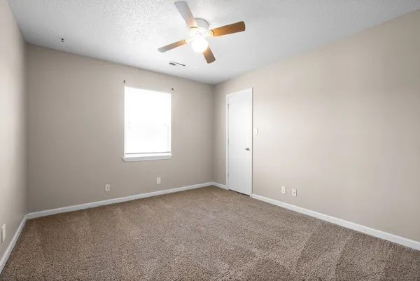an empty room with windows and fan