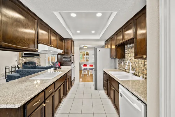 a kitchen with stainless steel appliances granite countertop a sink and a refrigerator