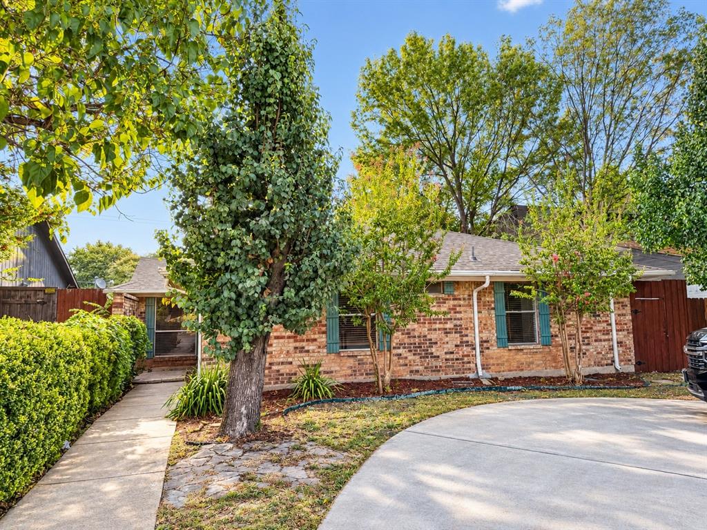 17922 Hillcrest Road Dallas, TX 75252 - Photo 1 of 11 Brick exterior with contrasting green shutters, mature trees, manicured hedges, and a concrete driveway