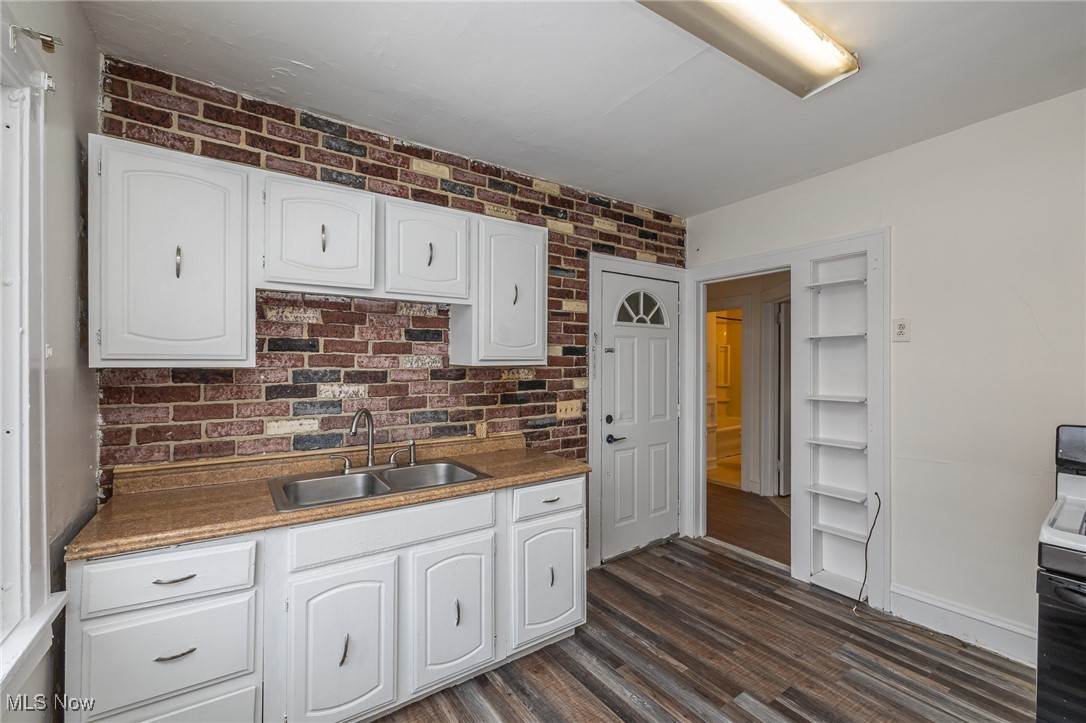 6003 Snow Road Parma, OH 44129 - Photo 2 of 28 Kitchen with white cabinetry, vinyl plank floors, stove, and brick wall