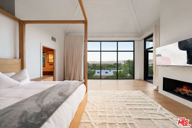 a large bedroom with a balcony a bed and a large window