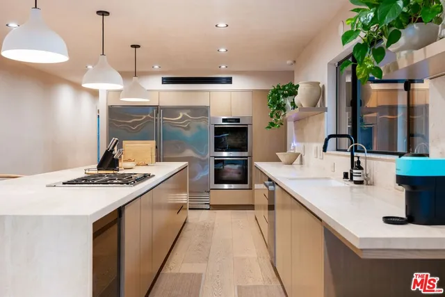 a kitchen with stainless steel appliances granite countertop a sink a stove and a wooden floors