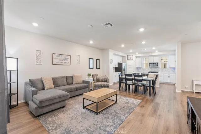 a living room with furniture wooden floor and a kitchen view