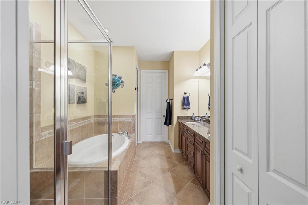 8986 Cambria Circle, Unit 2204 Naples, FL 34113 - Photo 14 of 36 a bathroom with a granite countertop shower a mirror and a sink